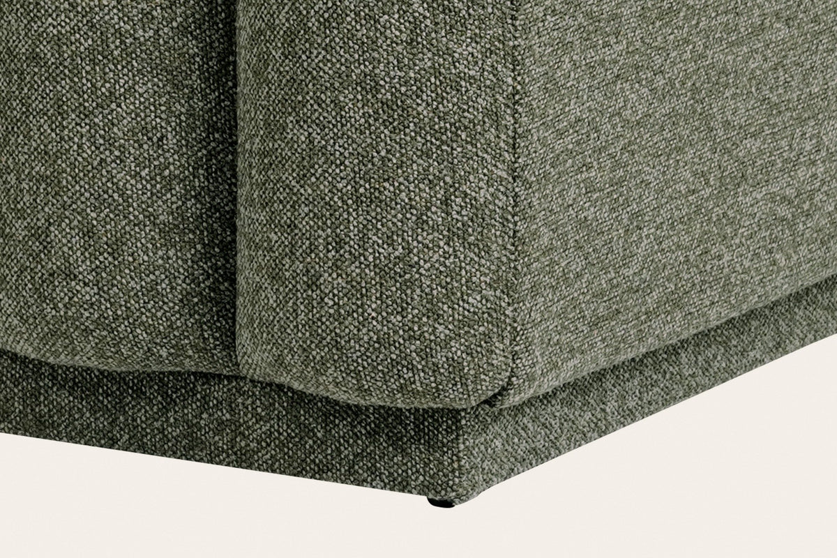 Close-up of the Abbadia base in moss: the channels end above a recessed upholstered plinth with a small foot at the corner