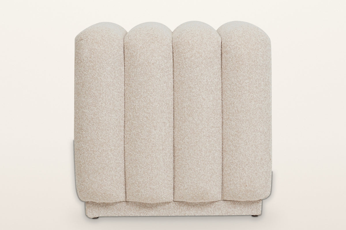 Abbadia ottoman in oat, straight view of the rounded ends of its four channels above the recessed plinth