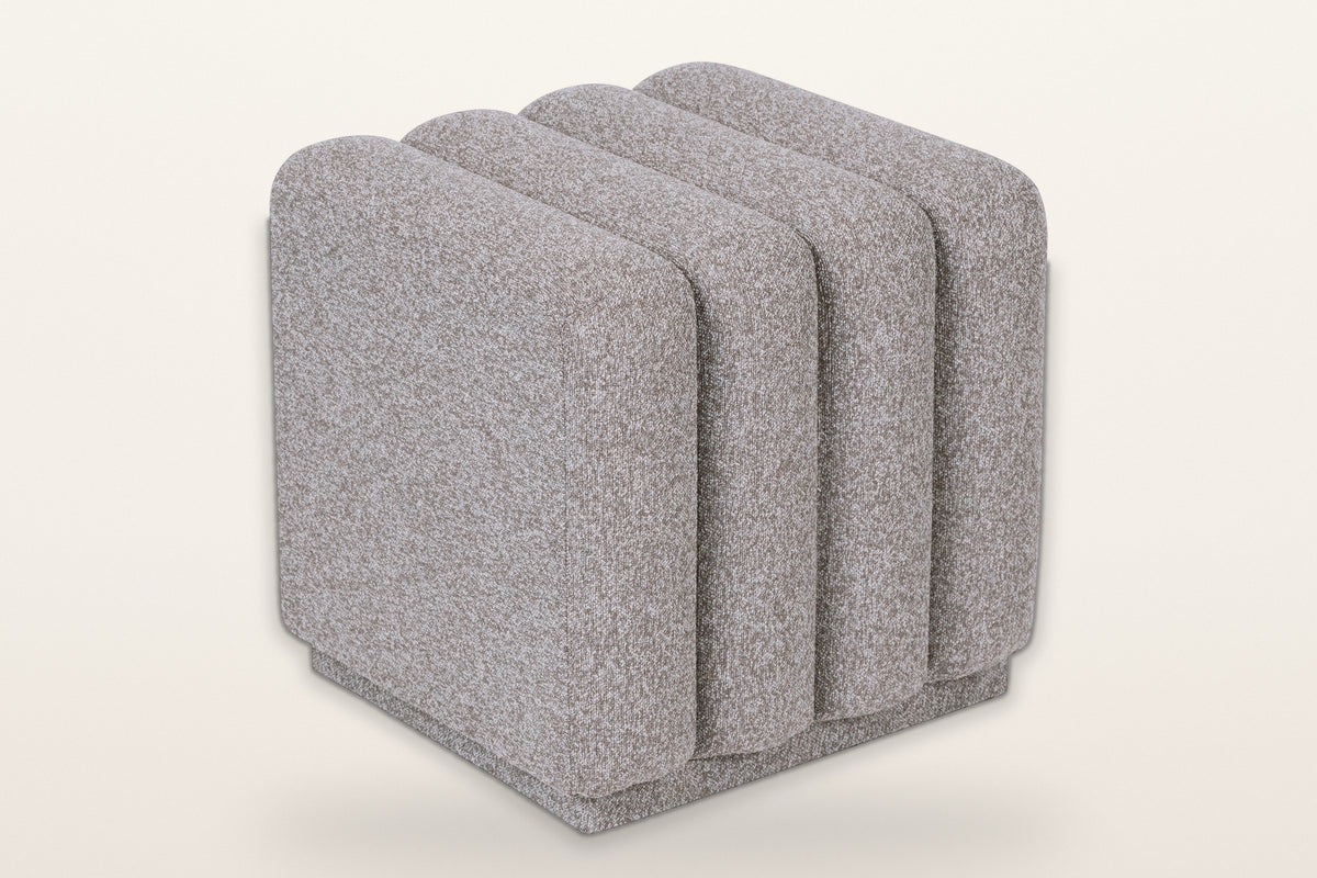 Abbadia channel-tufted square ottoman in stone, three-quarter view on a warm white studio backdrop