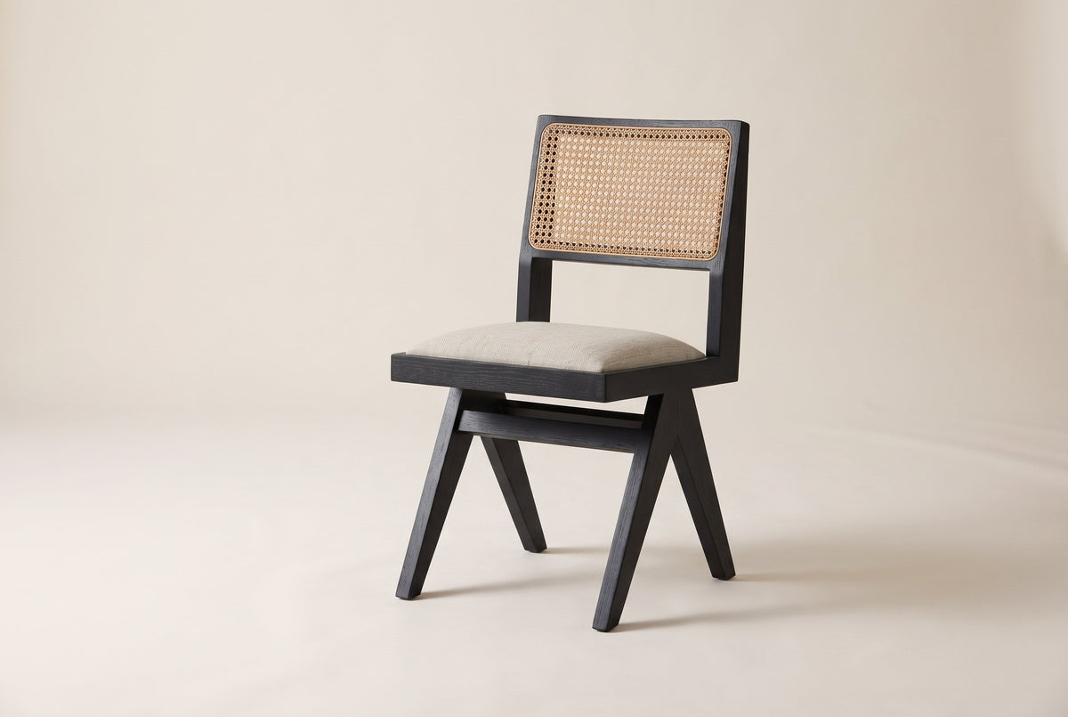 Alaya black oak dining chair with a cane back and oatmeal seat in three-quarter side view on an off-white studio backdrop