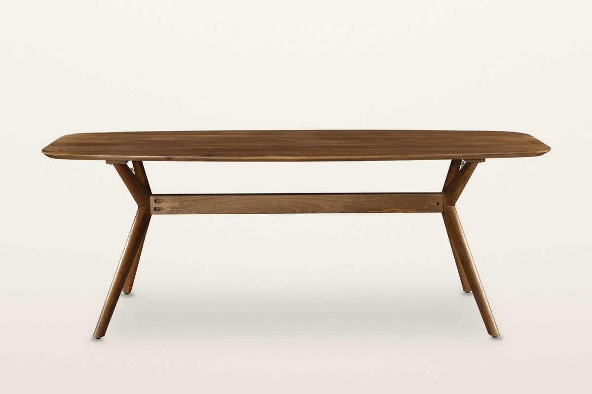 Amandola dining table in Light Walnut, straight front view on a warm white studio backdrop: a long rounded top on crossed leg