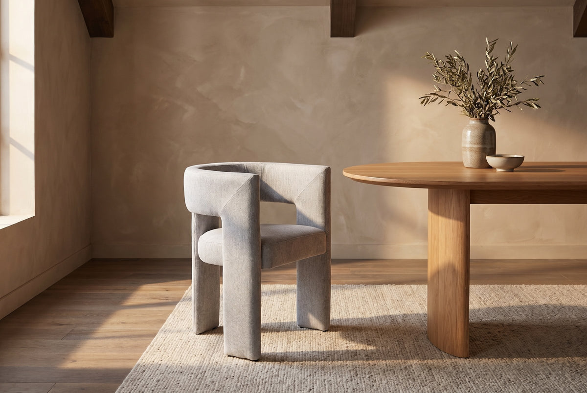 Andrea light grey woven fabric dining chair beside an oval oak table in a room with timber ceiling beams