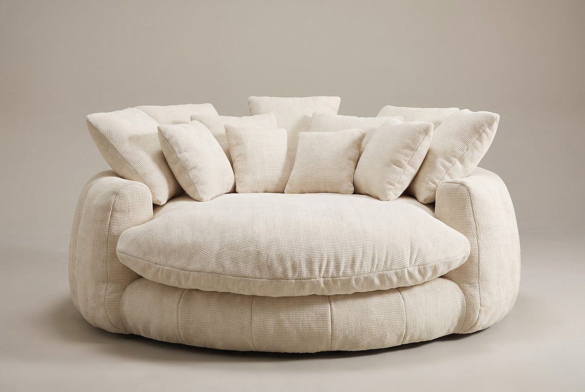 Aosta lounge chair in beige, straight front view: one thick round seat cushion inside a low channelled ring, square pillows along the back