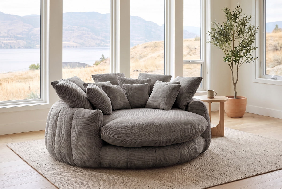 Aosta lounge chair in a Kelowna lake-house living room in the morning, the lake and dry hills beyond the windows (Grey)