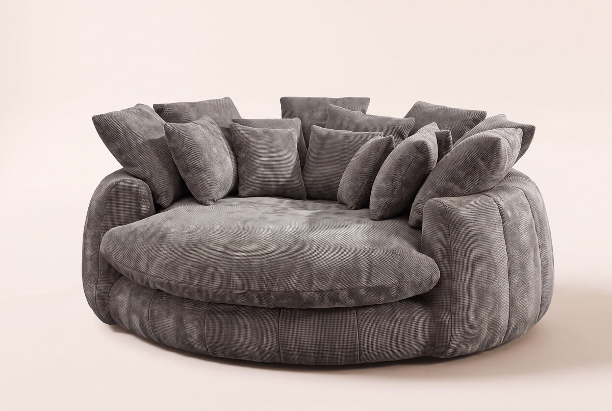 Aosta oversized round lounge chair in grey chenille, three-quarter view on a warm cream studio backdrop