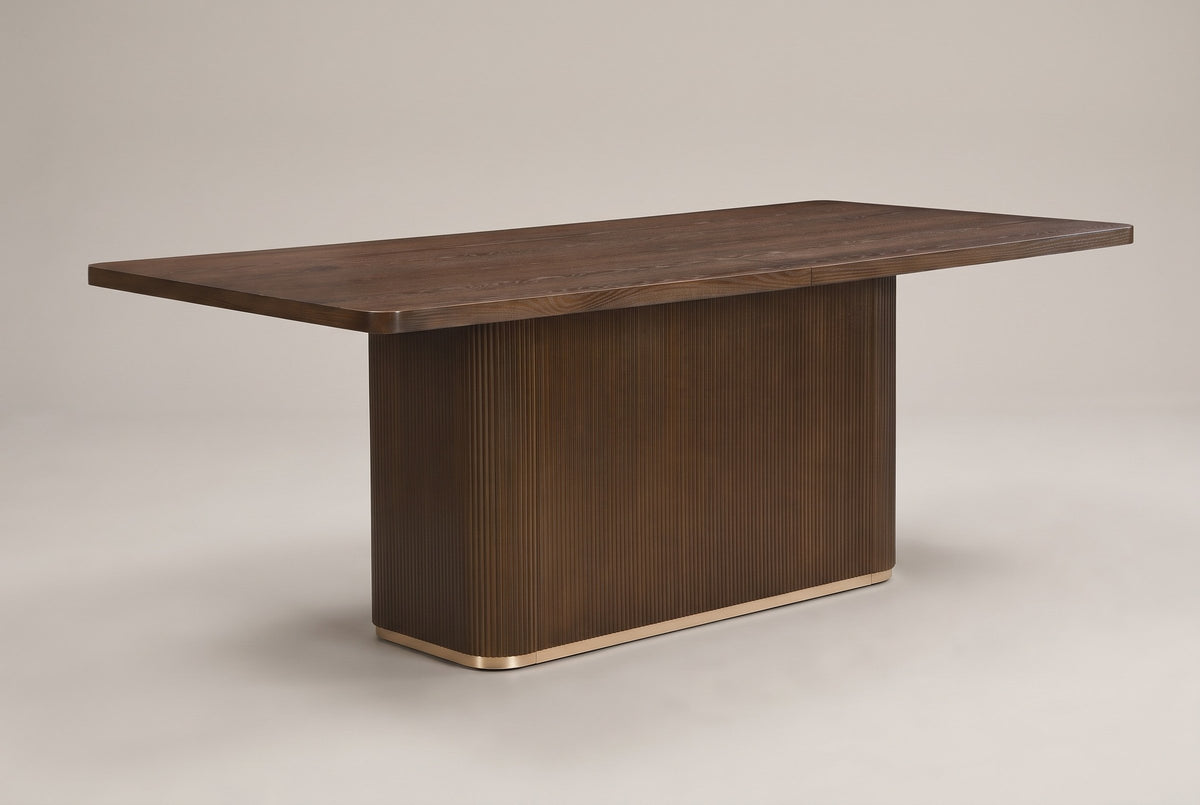 Aquileia 84-inch fluted pedestal dining table in Walnut, three-quarter view on a warm grey studio backdrop