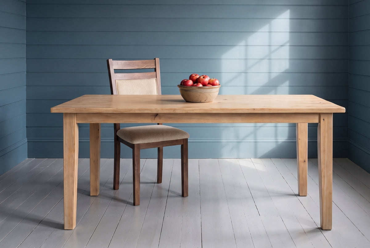 One Arden dining chair behind a scrubbed pine table in a room with harbour-blue plank walls and a grey painted floor, with a bowl of red apples