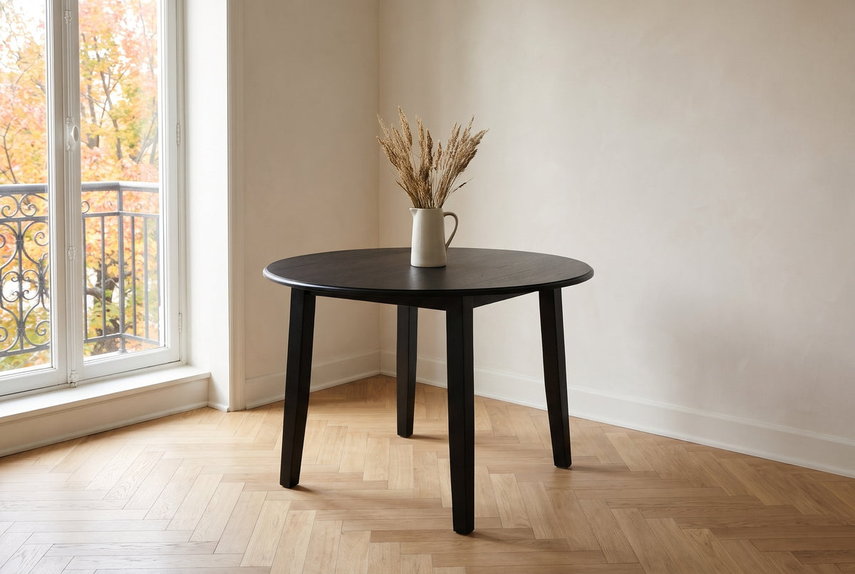 Arden drop-leaf dining table in Black with a jug of dried grasses, in the corner of a Plateau Mont-Royal apartment in Montreal, autumn maples beyond the balcony