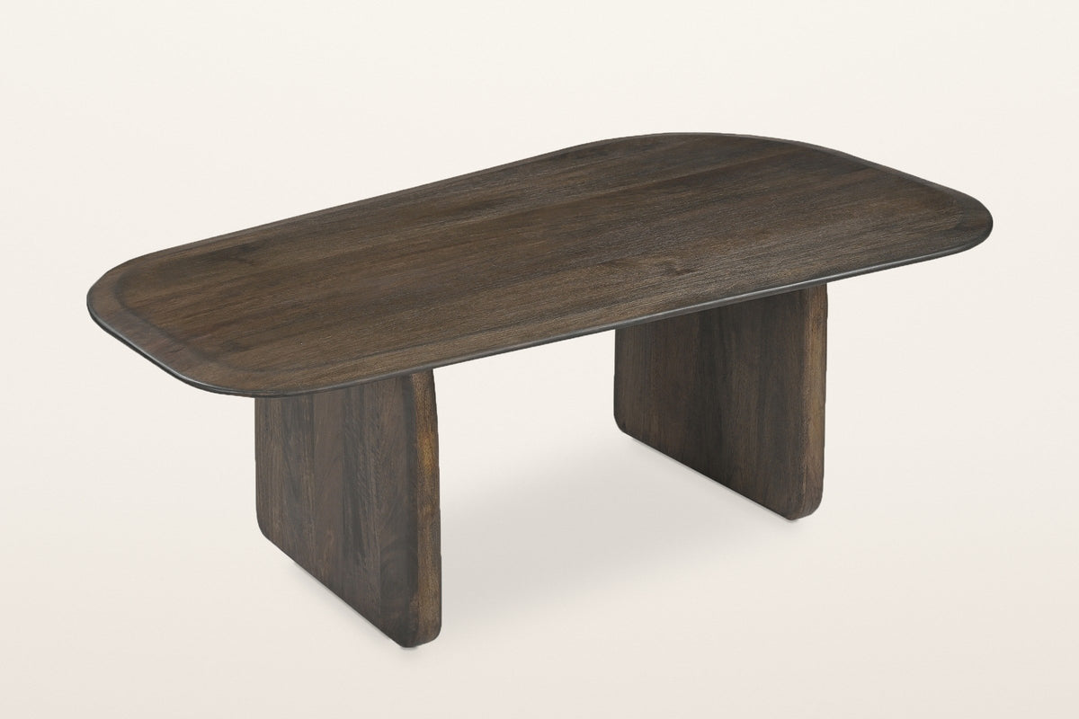 Arquata organic slab-leg coffee table in solid mango wood, mocha finish, three-quarter view on a warm white studio backdrop