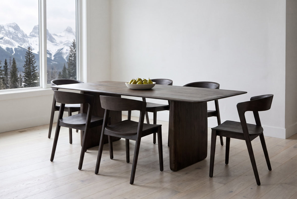 Arquata 7-piece dining set in mocha in a Canmore mountain-home dining room, snowy Rocky Mountain peaks through a tall window, a bowl of pears on the table