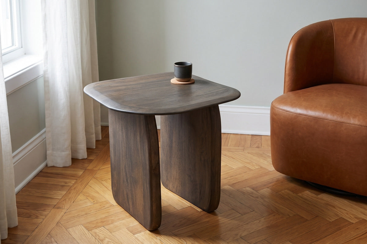 Arquata side table in mocha beside a cognac leather chair in a Montreal apartment with a grey-green wall and a herringbone fl