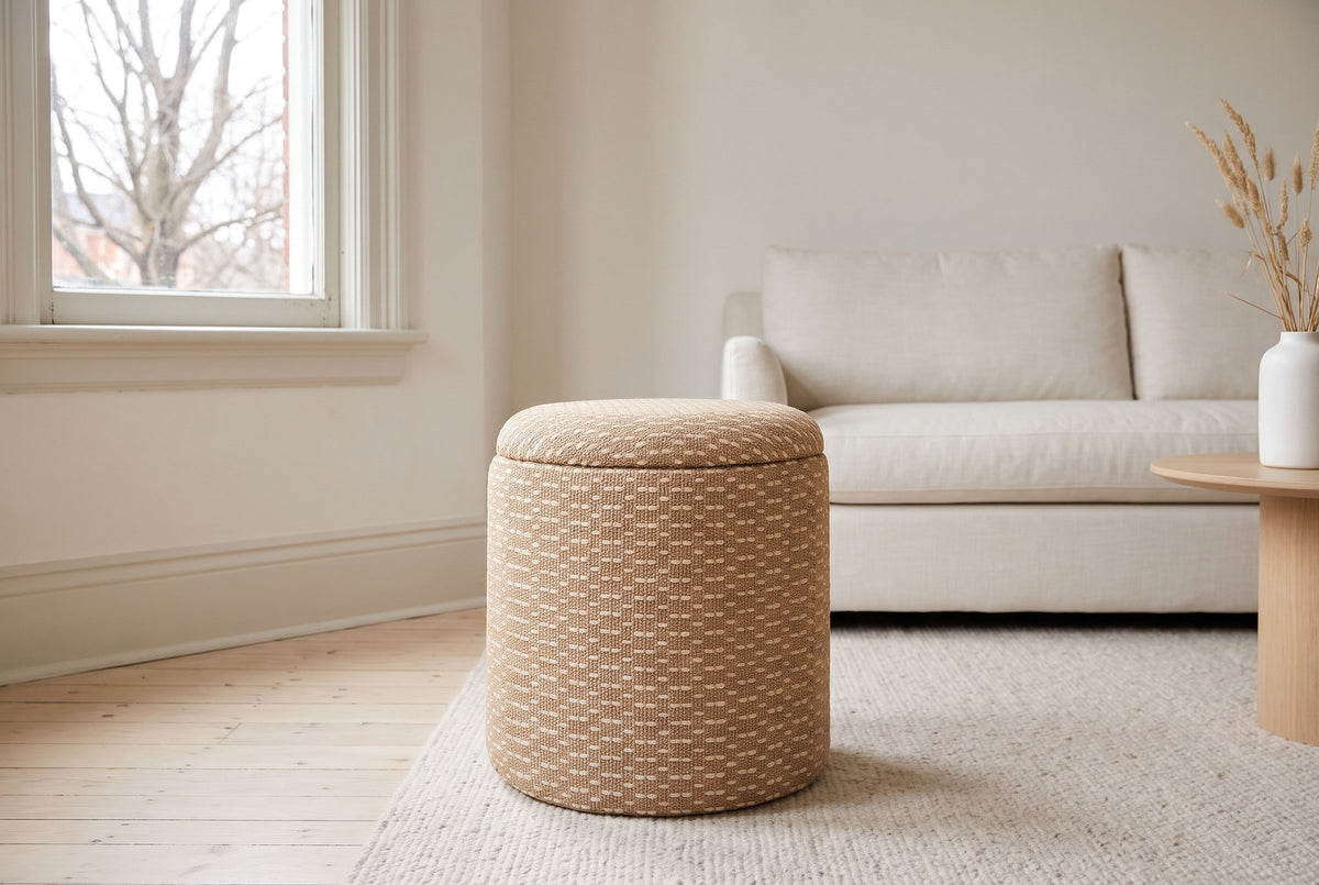 An Arvier pouf in Camel on an oatmeal wool rug in an Edwardian living room in the Glebe, Ottawa, an ivory linen sofa behind and a bare maple through the sash window
