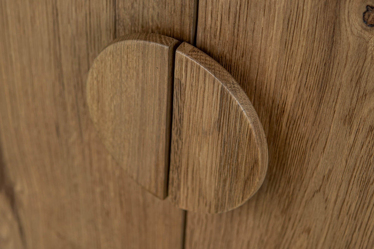 Close-up of the Atzara round pull in Natural, split in half where two oak doors meet
