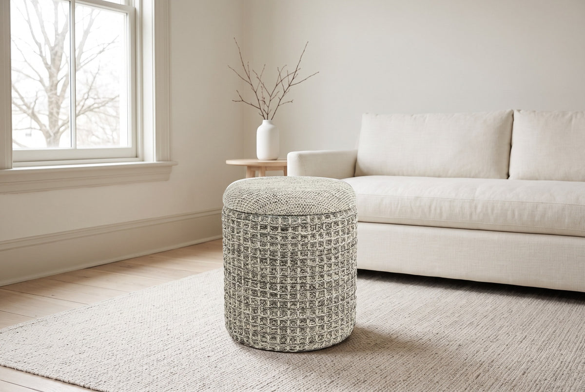 A Balme pouf in Charcoal on an oatmeal wool rug in a Victorian living room in the South End of Halifax, an ivory linen sofa behind and a bare maple through the sash window