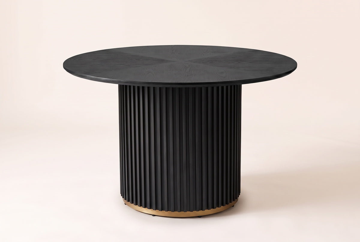 Bardolino round fluted pedestal dining table in black, three-quarter view on a warm off-white backdrop