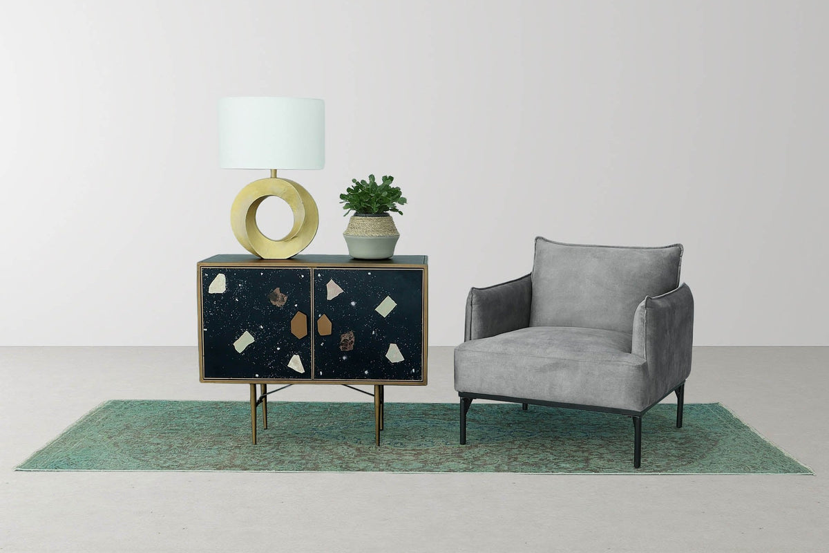 Bastien table lamp on a dark cabinet beside a grey accent chair