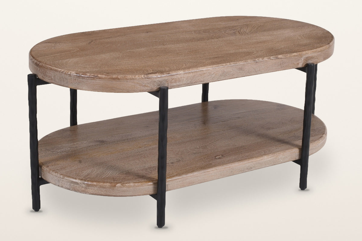 Bellano oval mango wood coffee table, three-quarter view from above on a warm white studio backdrop