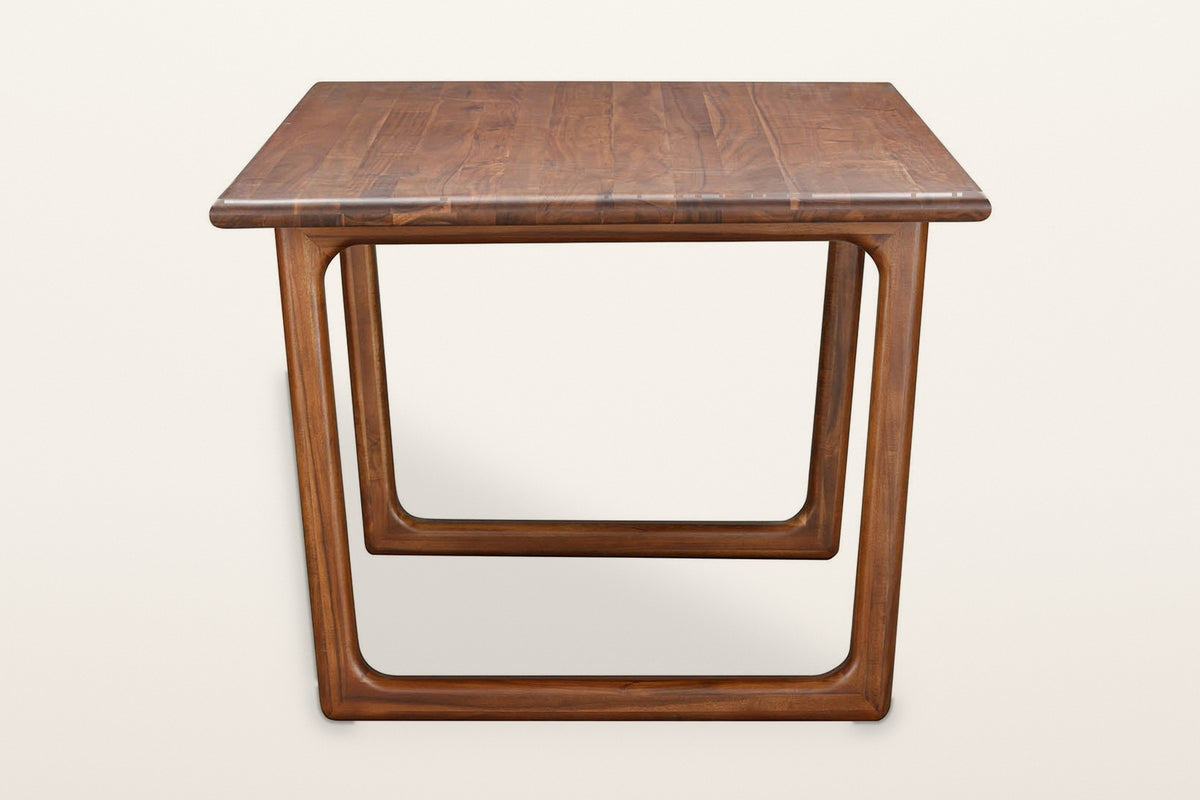 End view of the Bernalda dining table in Honey Brown on a warm white studio backdrop: one closed-loop frame
