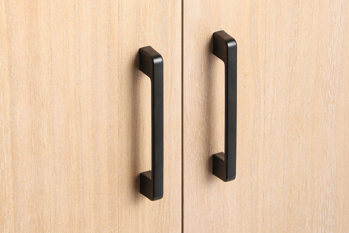 Close-up of two matte black metal bar pulls at the meeting edge of two pale natural wood veneer doors