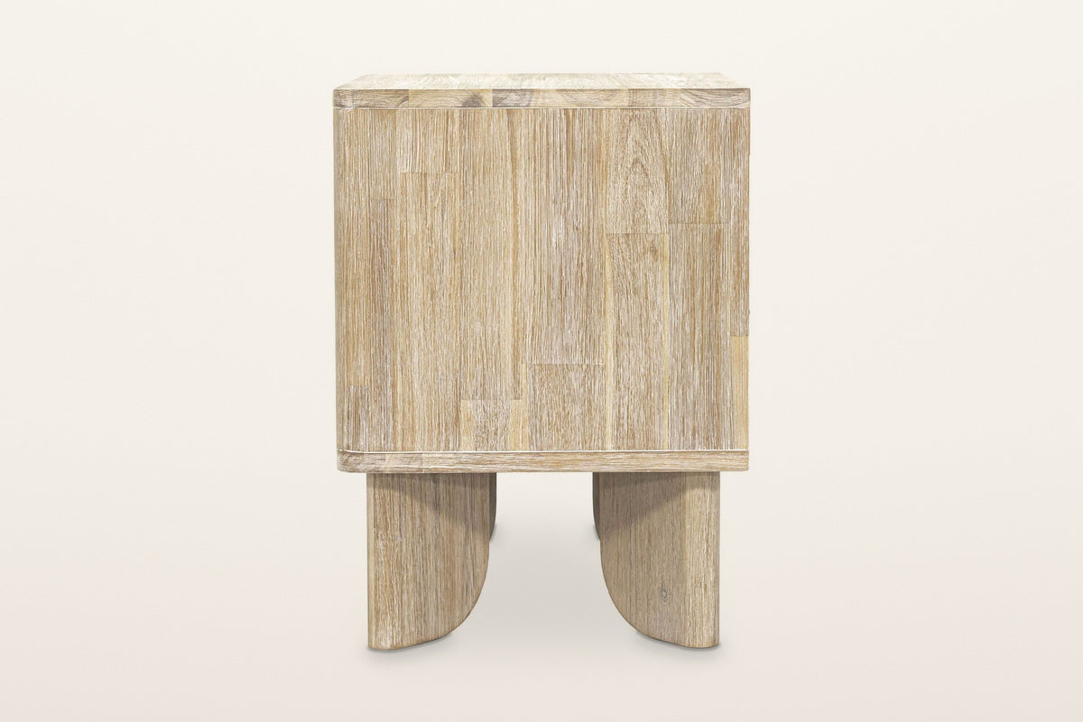 Side view of the Bienno nightstand in Sand Wash on a warm white studio backdrop: a plain finger-jointed side panel over two f