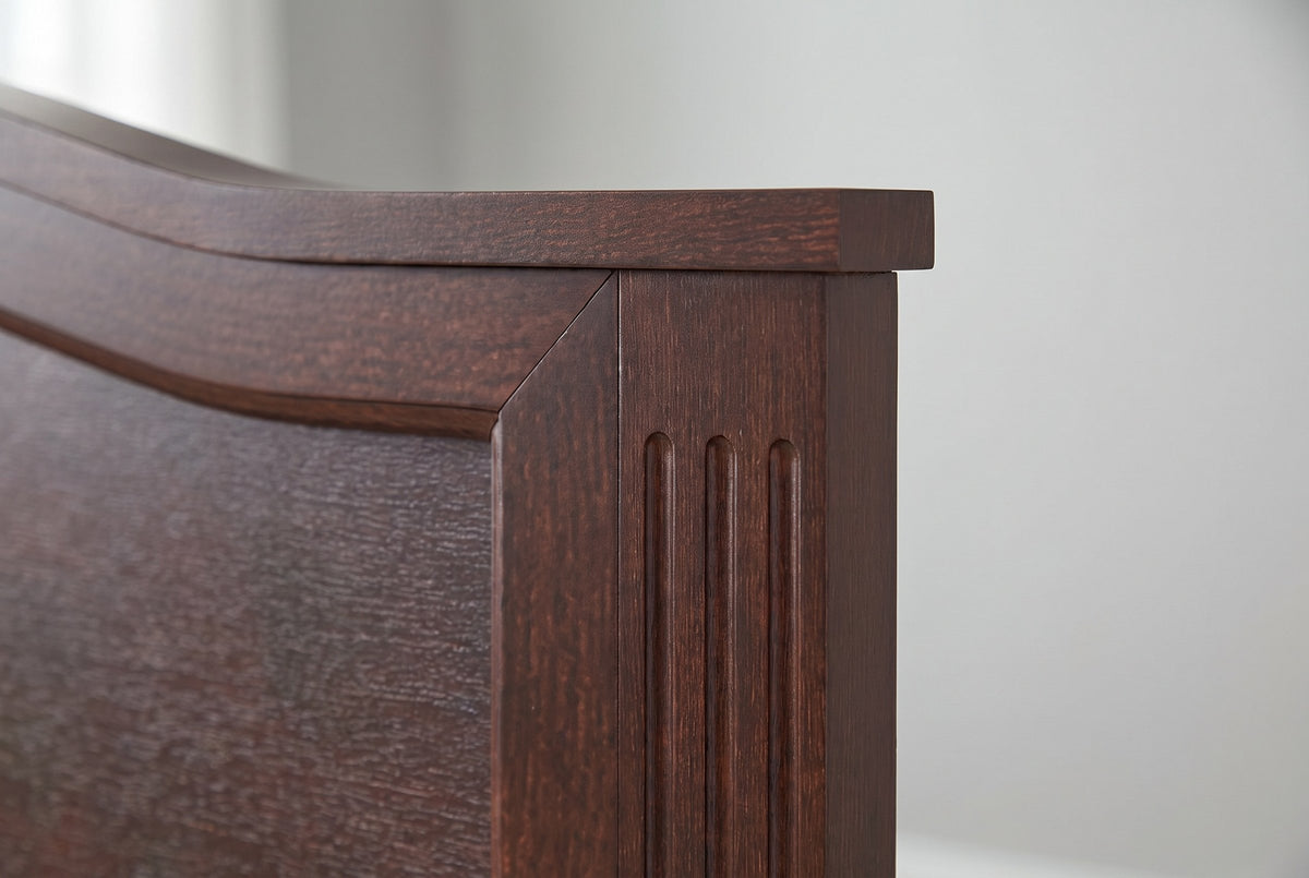 Close-up of the Bolsena headboard corner: the crest cap overhanging a fluted square post