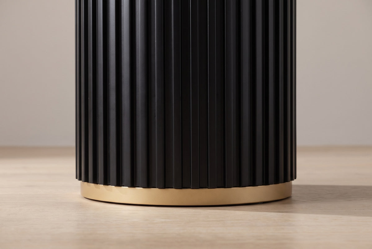Close-up of the black fluted drum ending just above a plain gold-toned metal ring on a pale oak floor