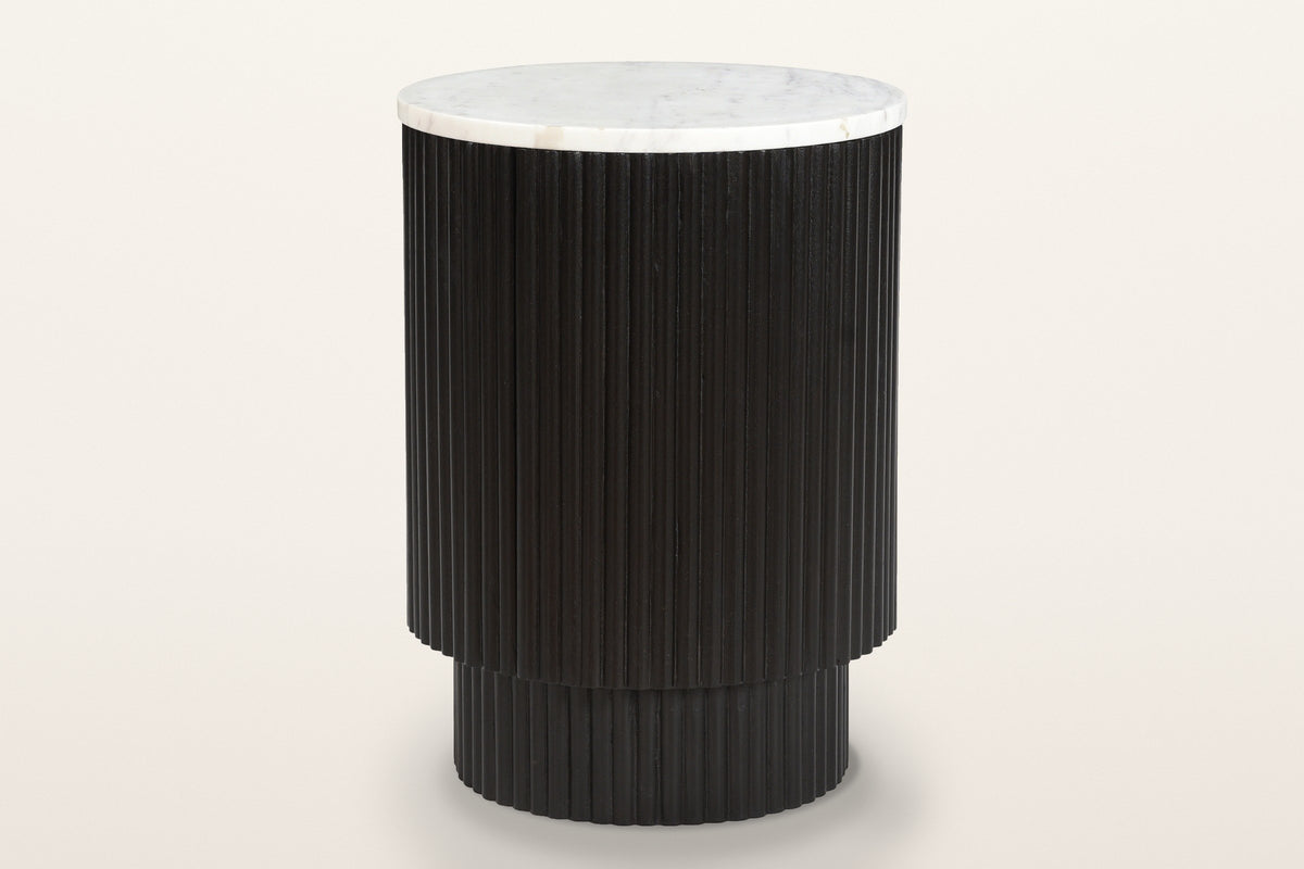 Bomarzo reeded mango wood side table in black with a white marble top, three-quarter view on a warm white studio backdrop