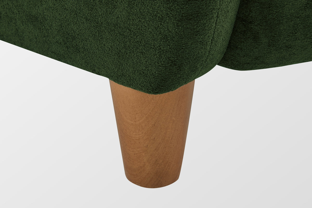 Close-up of a tapered solid birch leg in a teak finish under the velvet corner (Olive Green)