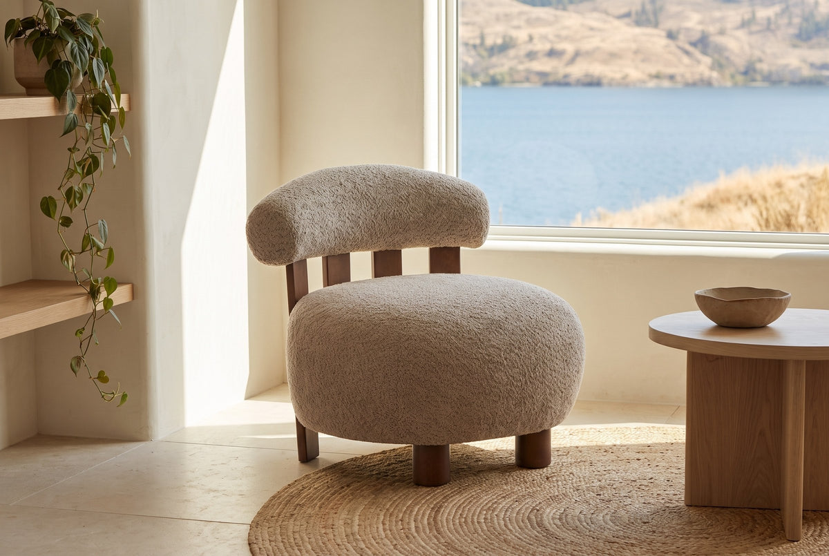 Brescia boucle accent chair on a round jute rug in a bright lake house, the lake and hills through the window