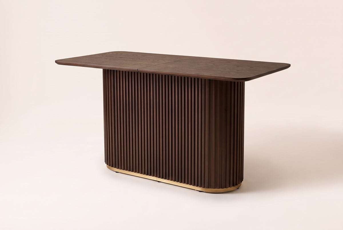 Brugnato counter height table in walnut, three-quarter view on a warm off-white backdrop