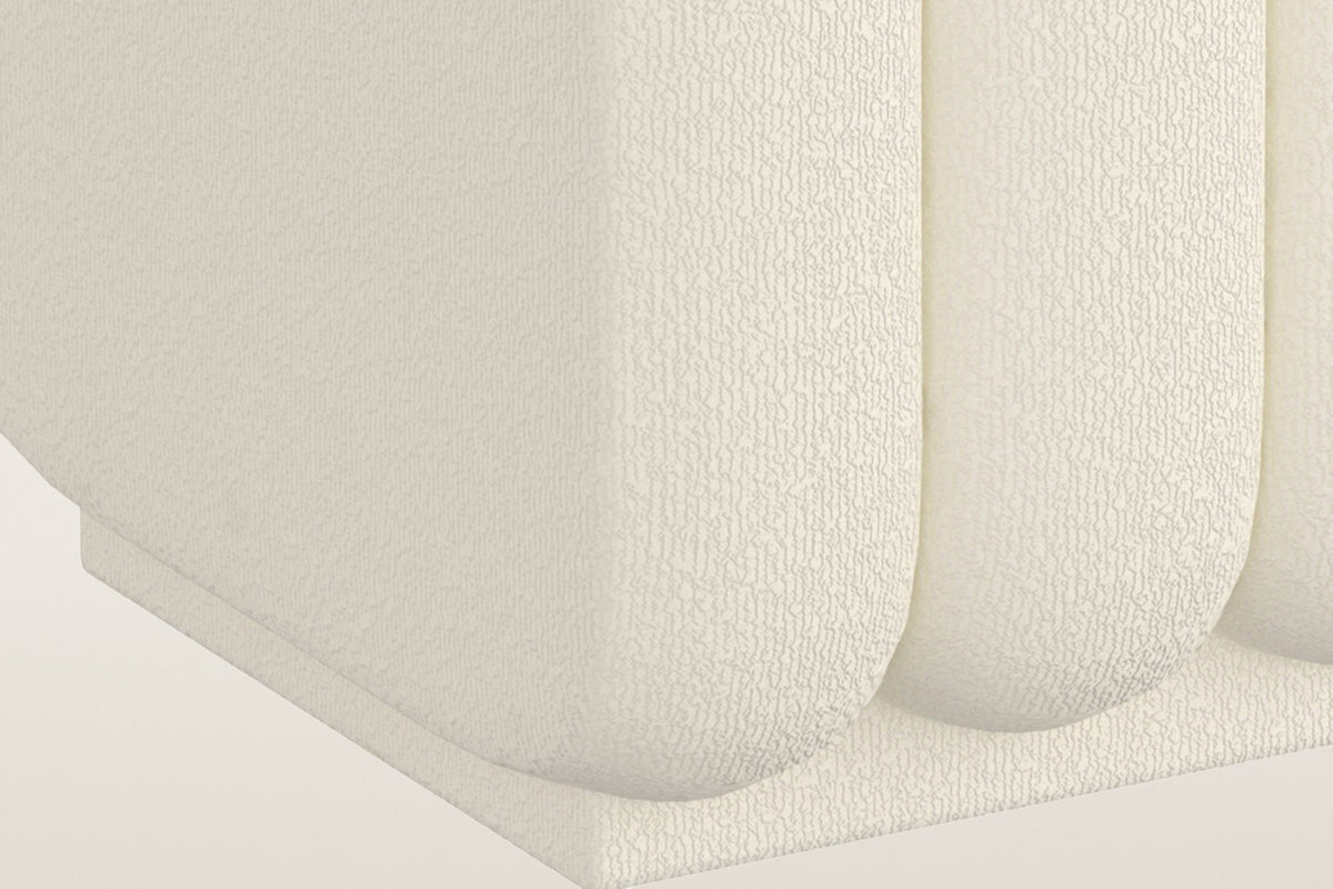 Brusson ottoman close-up: the rounded ends of the channels over the low boucle-covered plinth