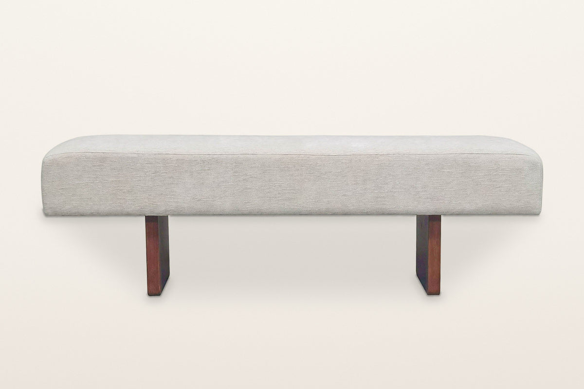 Caltagirone bench in Oatmeal Sand, straight front view on a warm white studio backdrop: the slab legs show only their edges