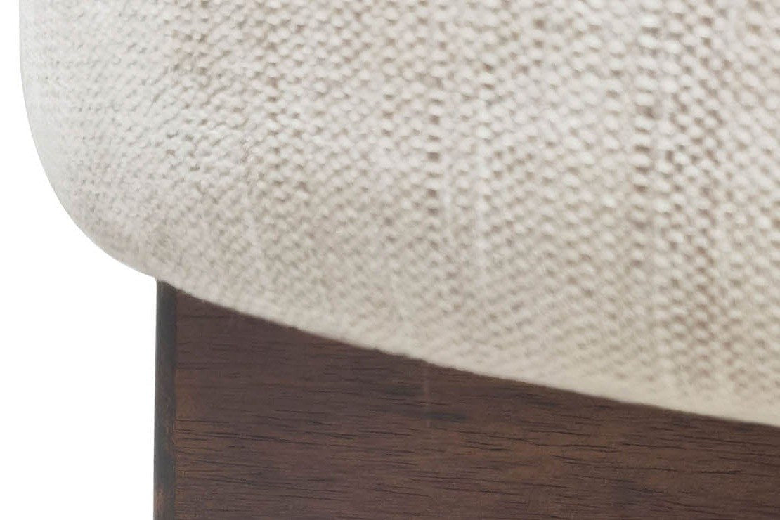 Close-up of the Caltagirone stool: the oatmeal fabric drum over one walnut slab of the cross base