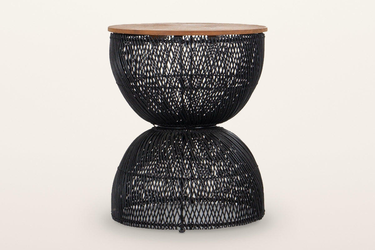Canale rattan hourglass side table in Black on a warm white studio backdrop: a round teak top on an open-weave black rattan h