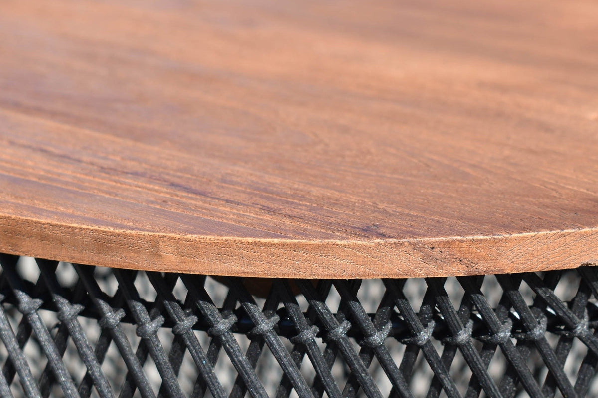 Close-up of the Canale side table in Black: the round reclaimed teak top over the open black rattan lattice