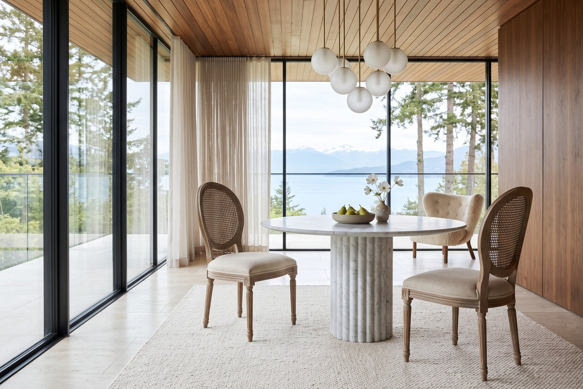 Two Candelo cane back dining chairs at a round fluted marble table in a Qualicum Beach house