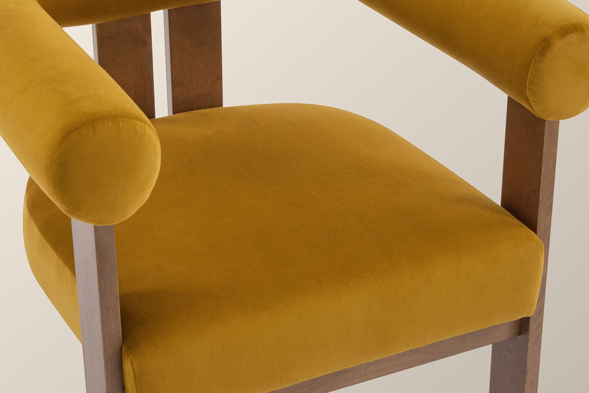 Close-up of the mustard yellow velvet seat and the flat round end of the arm