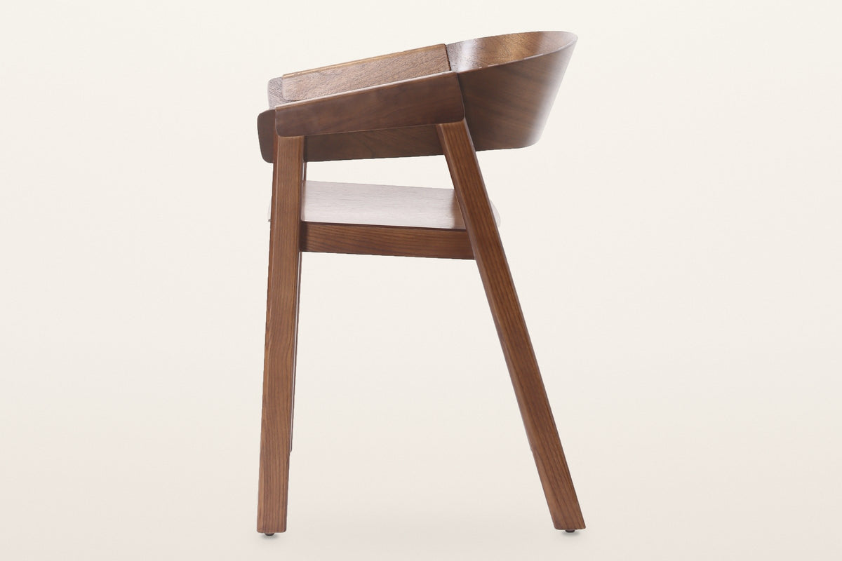 Caprarola dining armchair in walnut, side view: the back shell folding over the front leg and the raked back leg