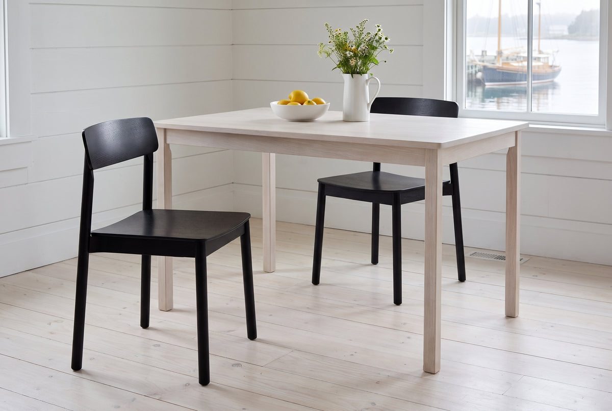 Two Casole dining chairs in black-stained oak at a pale oak table in a Lunenburg harbour house