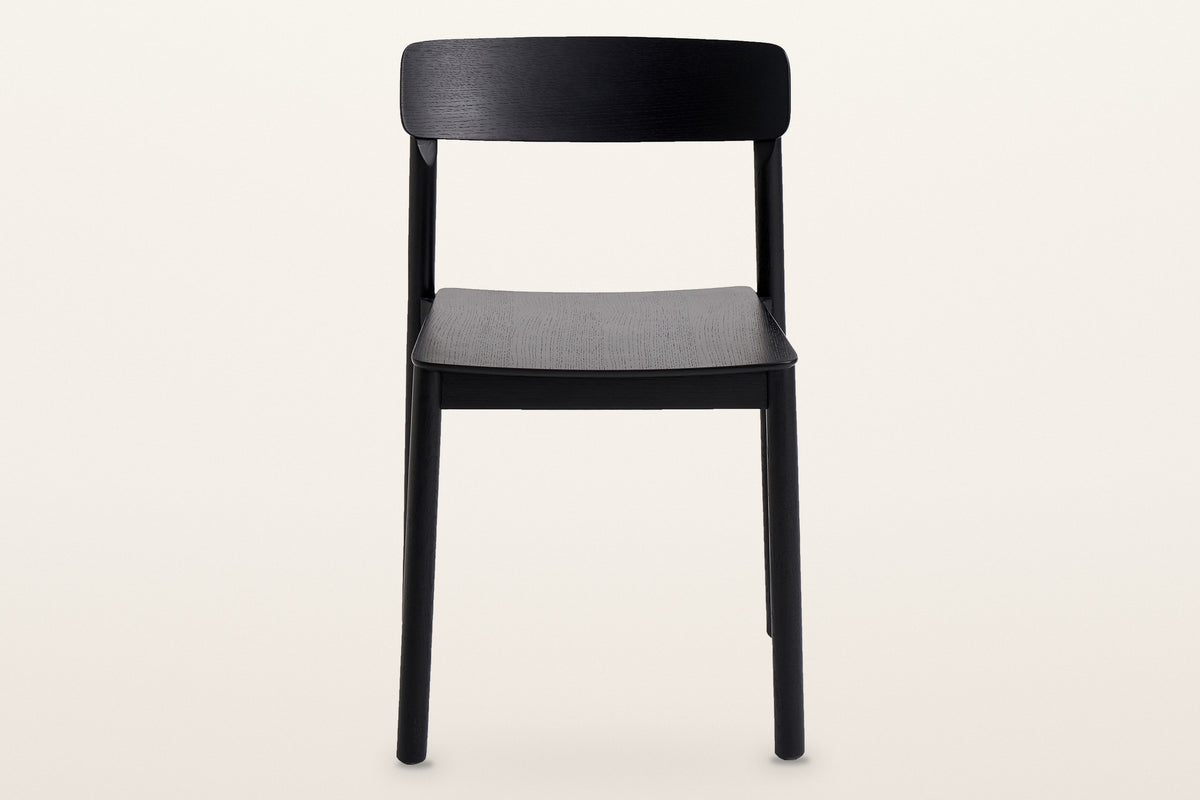 Casole dining chair in black-stained oak, straight front view on a warm white studio backdrop