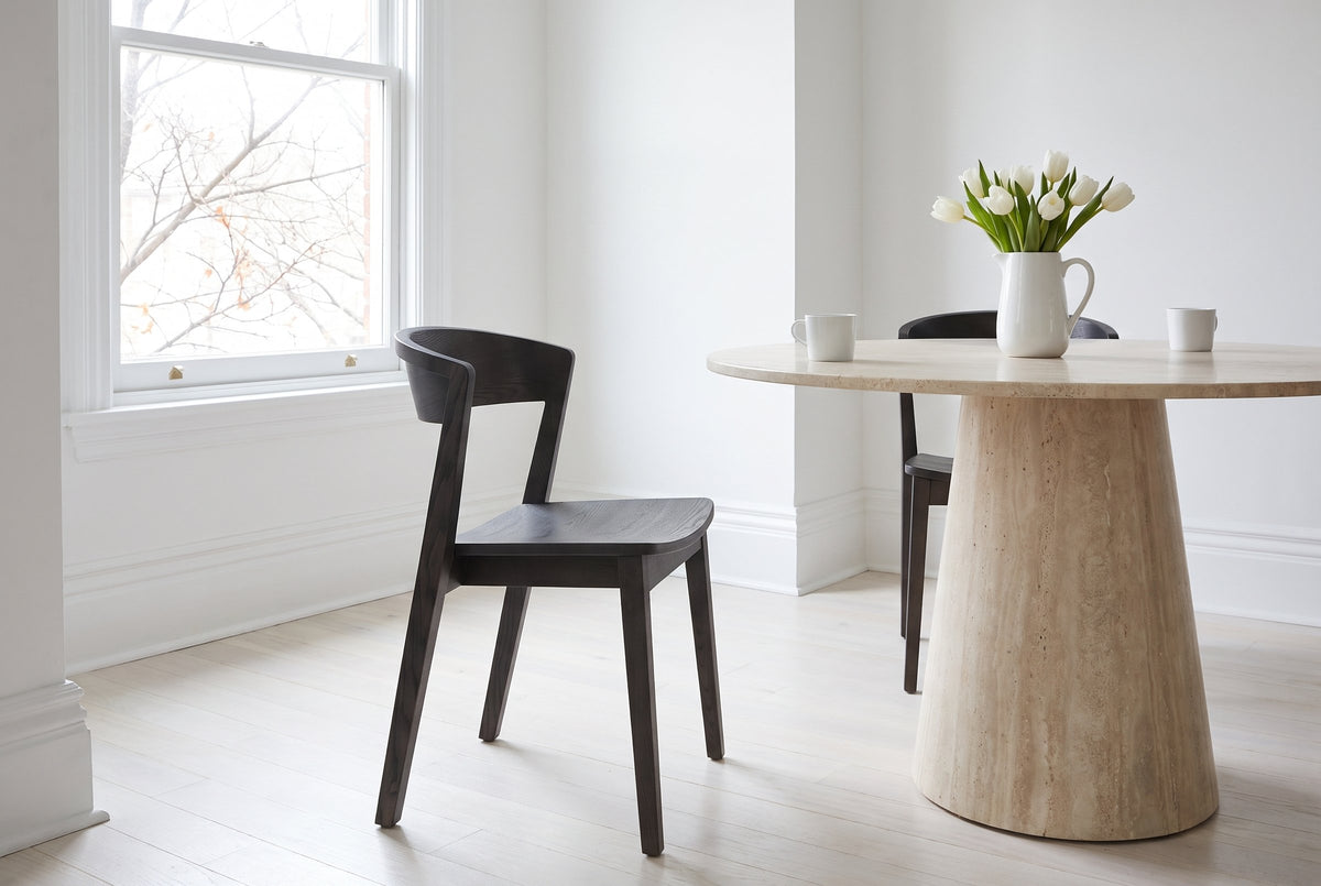 Two Certosa dining chairs in mocha at a round travertine pedestal table in a Toronto dining room