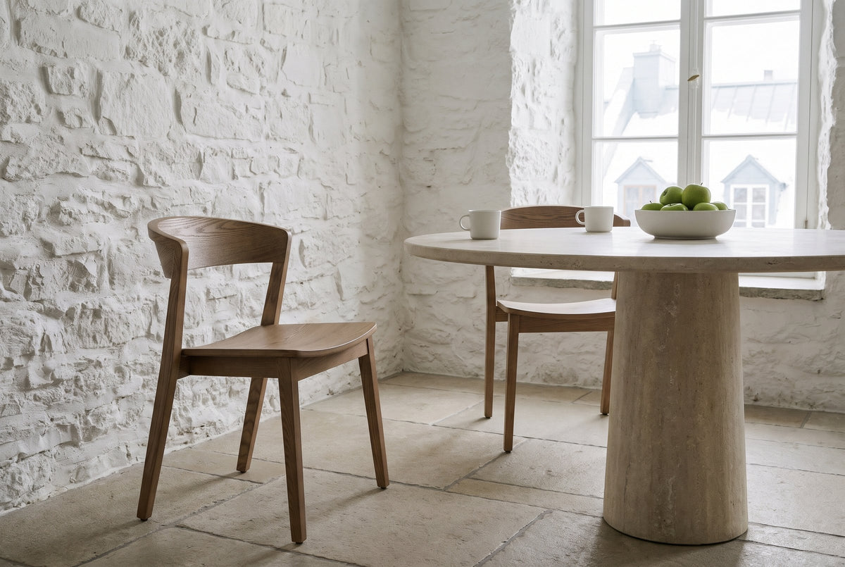 Two Certosa dining chairs in walnut at a round limestone table in an old Quebec City stone house