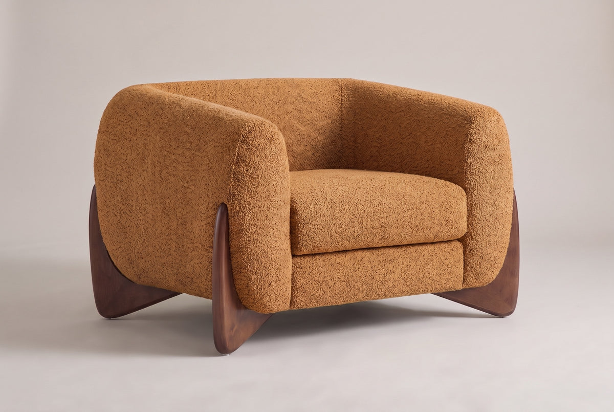 Cervia boucle lounge chair in Caramel, three-quarter view on a warm grey studio backdrop