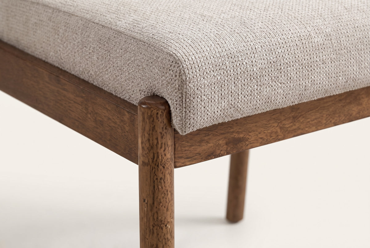 Close-up of a Cervo front leg in walnut: its rounded top beside the corner of the beige woven seat