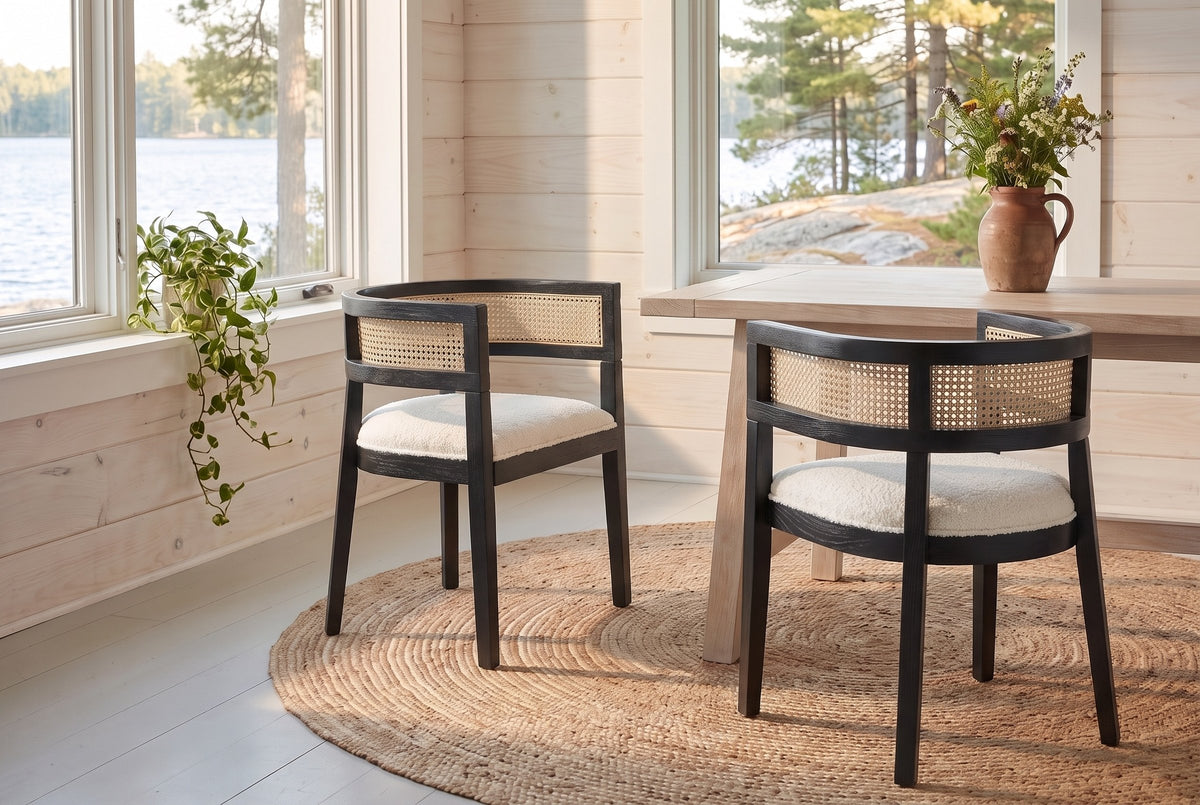 Two Cesena dining chairs in Black on a round jute rug in a Muskoka cottage dining nook with a view of the lake