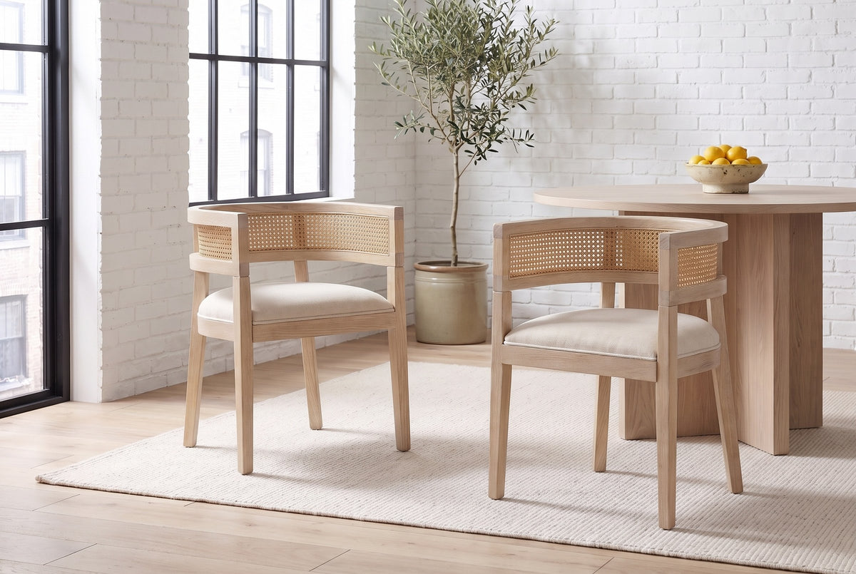 Two Cesena dining chairs in Natural Ash pulled out from a pale-oak pedestal table in a white-brick Montreal loft