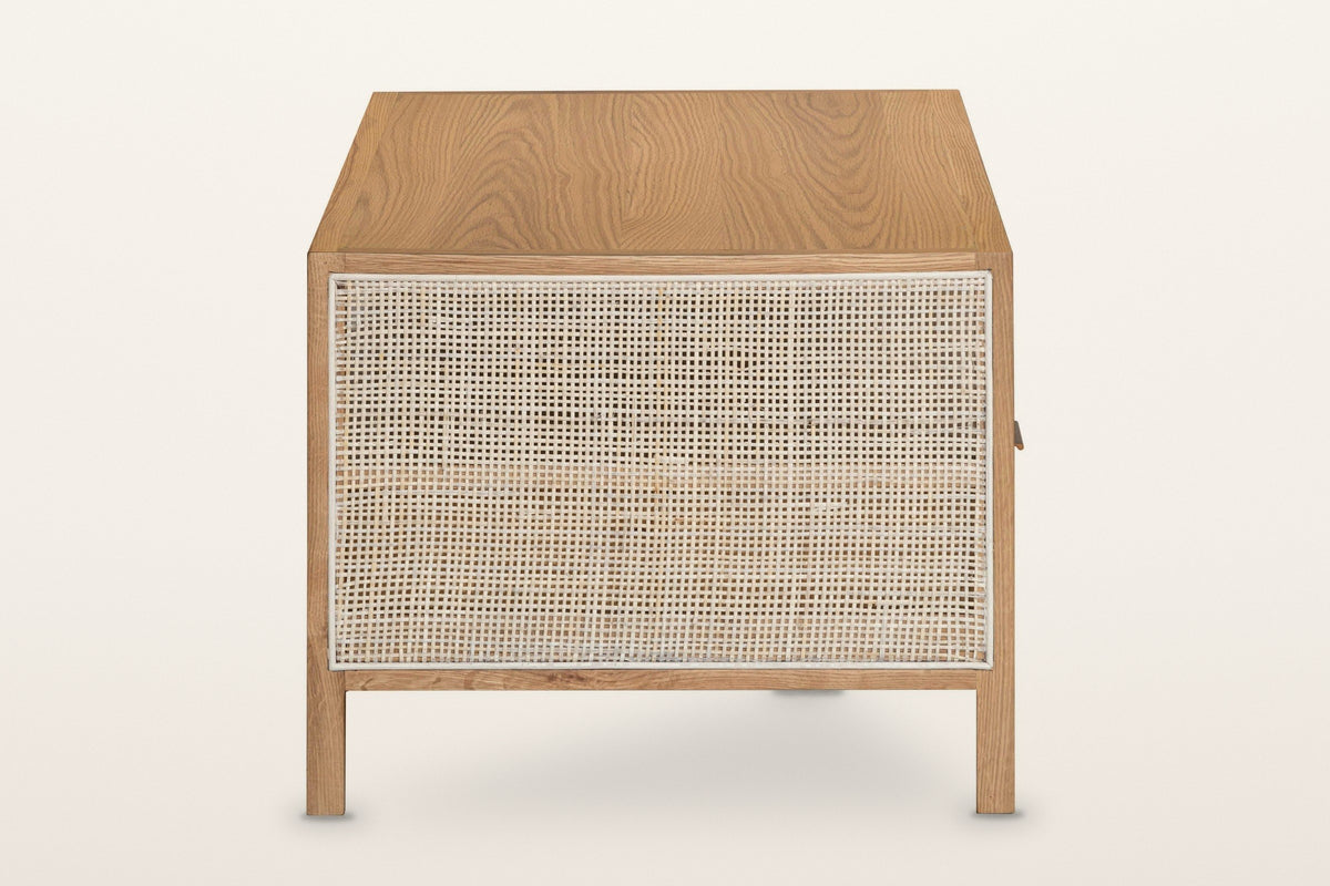 End view of the Cetara coffee table in Natural on a warm white studio backdrop: one tall framed wicker panel between two squa