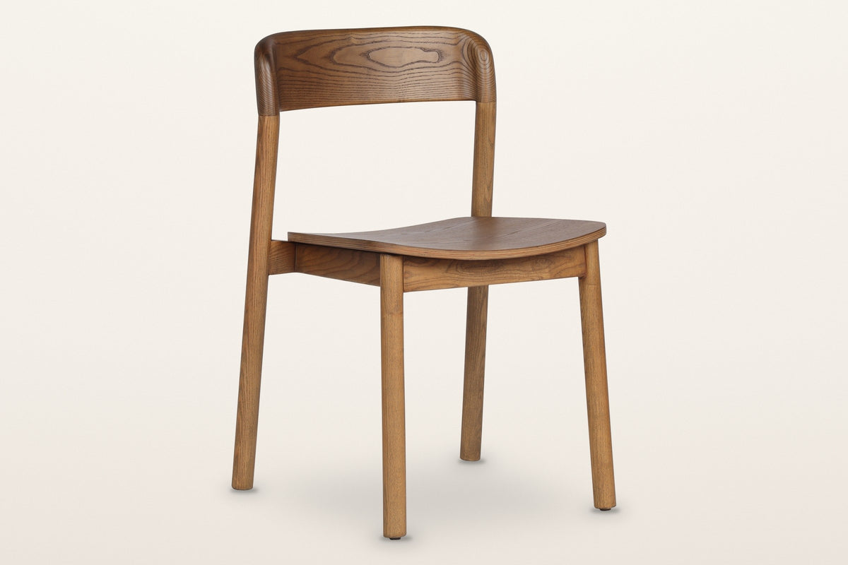 Chiavenna curved-back dining chair in walnut, three-quarter view on a warm white studio backdrop