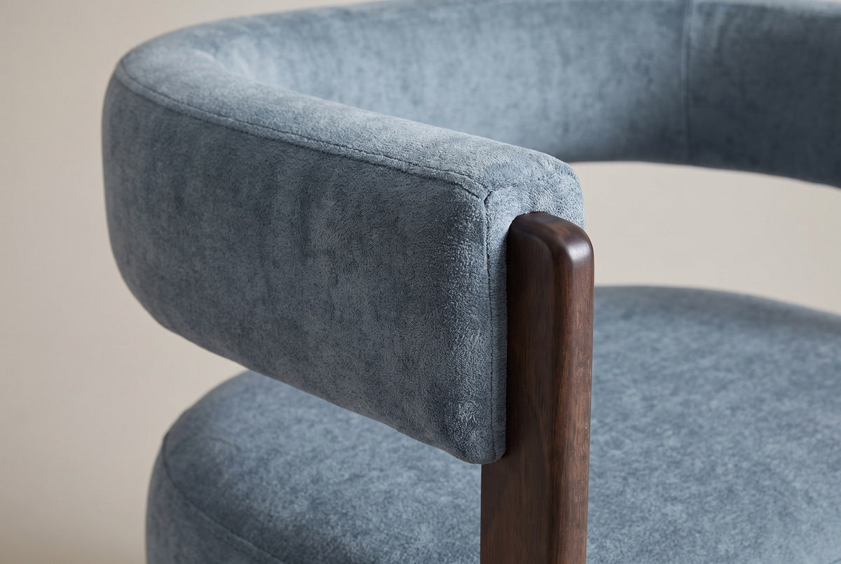 Close-up of the blue velvet back band ending on the rounded top of a walnut front leg