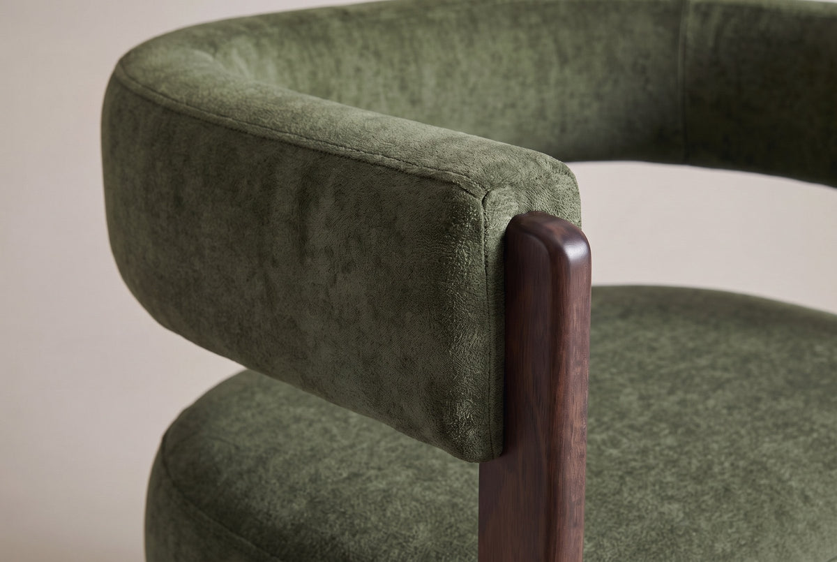 Close-up of the olive green velvet back band ending on the rounded top of a walnut front leg